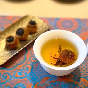 A white cup filled with clear, golden tea liquor. The image represents a clean fruit-tea aroma where tangy-sweet Chestnut Rose weaves with the rich fragrance of Dianhong black tea.