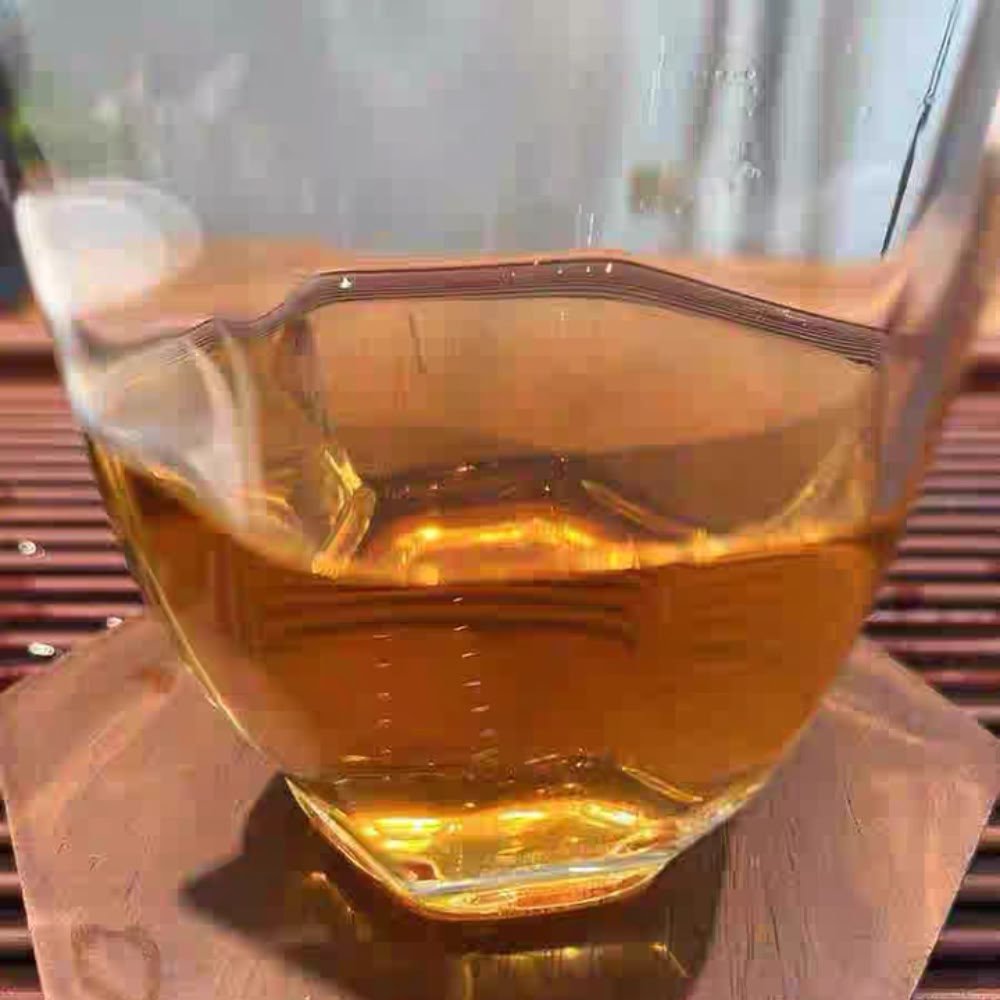 Clear amber-colored infusion of Lily Pagoda Bloom black tea in a glass cup, highlighting its premium quality and lily aroma.