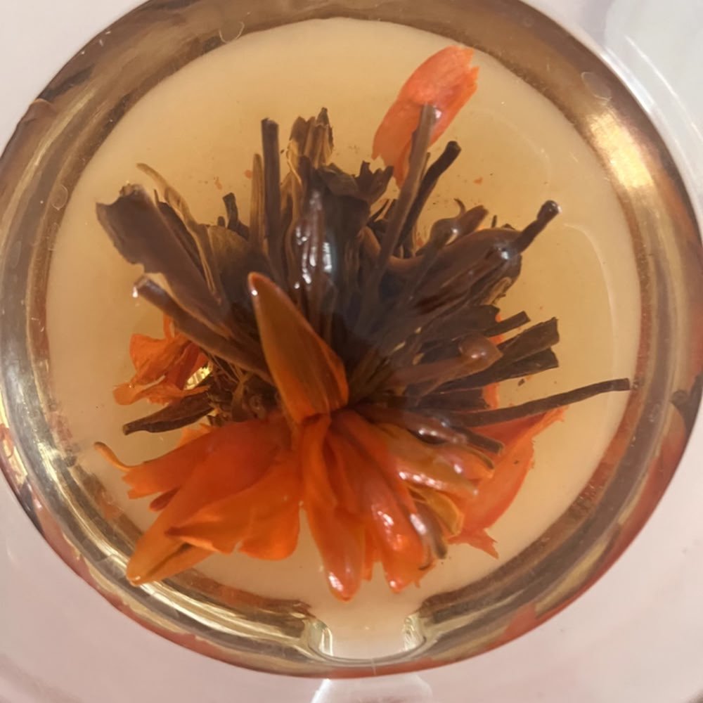 A close-up top view of the Lily Pagoda Bloom tea flower, showing its neat petals and clear infusion that carries a natural honey and floral aroma.