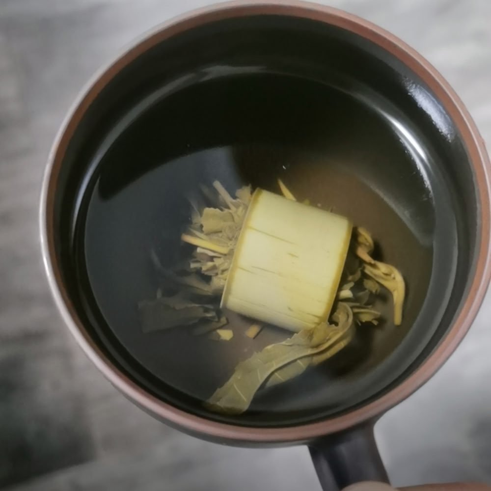 A top-down view from a customer showing the bamboo Pu'er tea steeping beautifully in a casual dark ceramic mug.